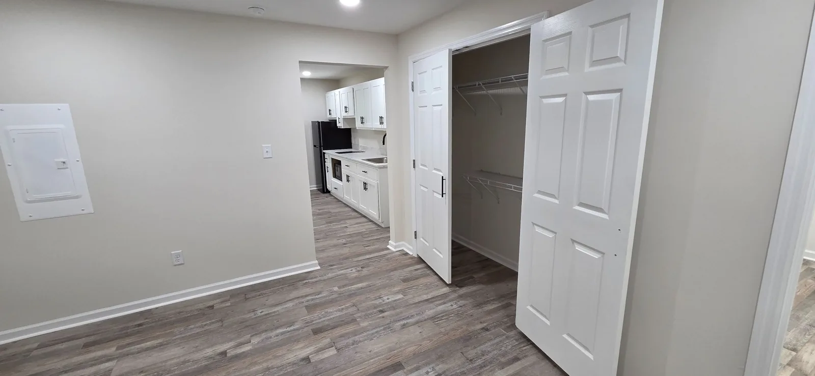 A Marlboro bedroom with double closet doors standing open and the kitchen visible beyond.