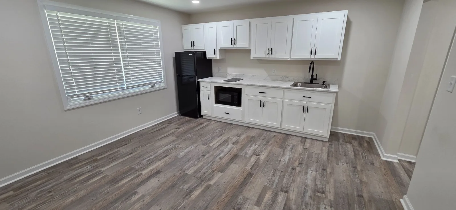 Open kitchen and living area in a Marlboro apartment with a window and plank flooring.