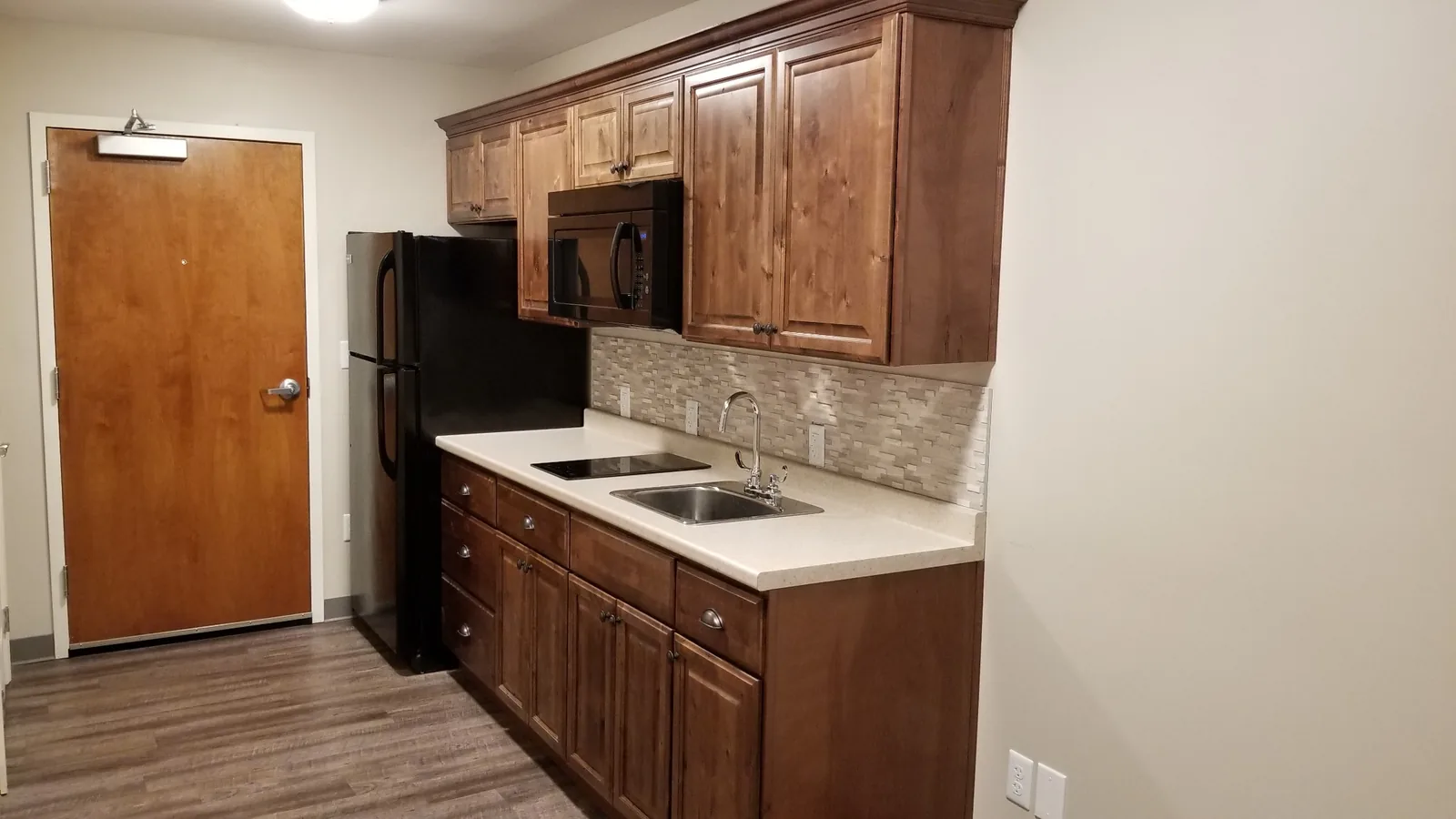 Kitchen cabinetry and counter seen from the apartment entry door.