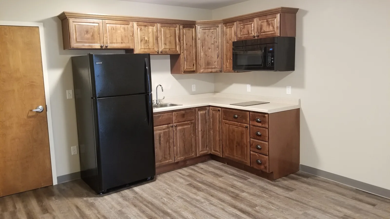 A Silverdale apartment kitchen with wood cabinets, refrigerator, cooktop and over-range microwave.