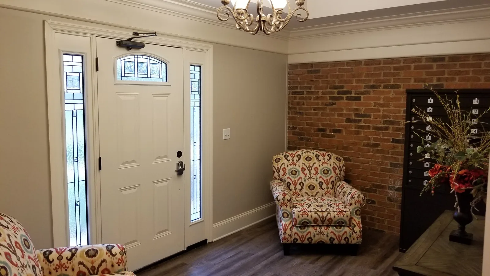 The Silverdale lobby looking toward the glass-panelled front door, with armchairs and an exposed brick wall.