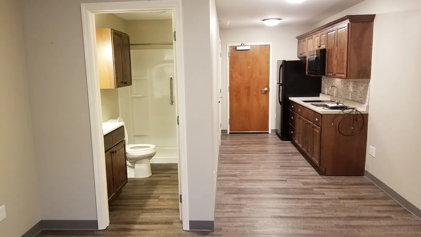 A Silverdale studio apartment looking from the living space through to the bathroom and kitchen.